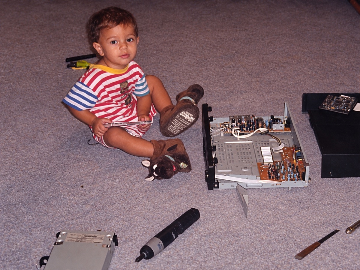 William as a child, sitting with tools beside an open computer.